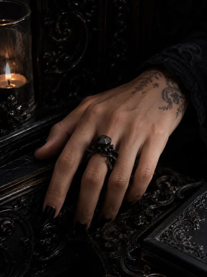 Detail of the Brutalist metal solitaire ring's faceted metal stone and architectural prongs in oxidized silver