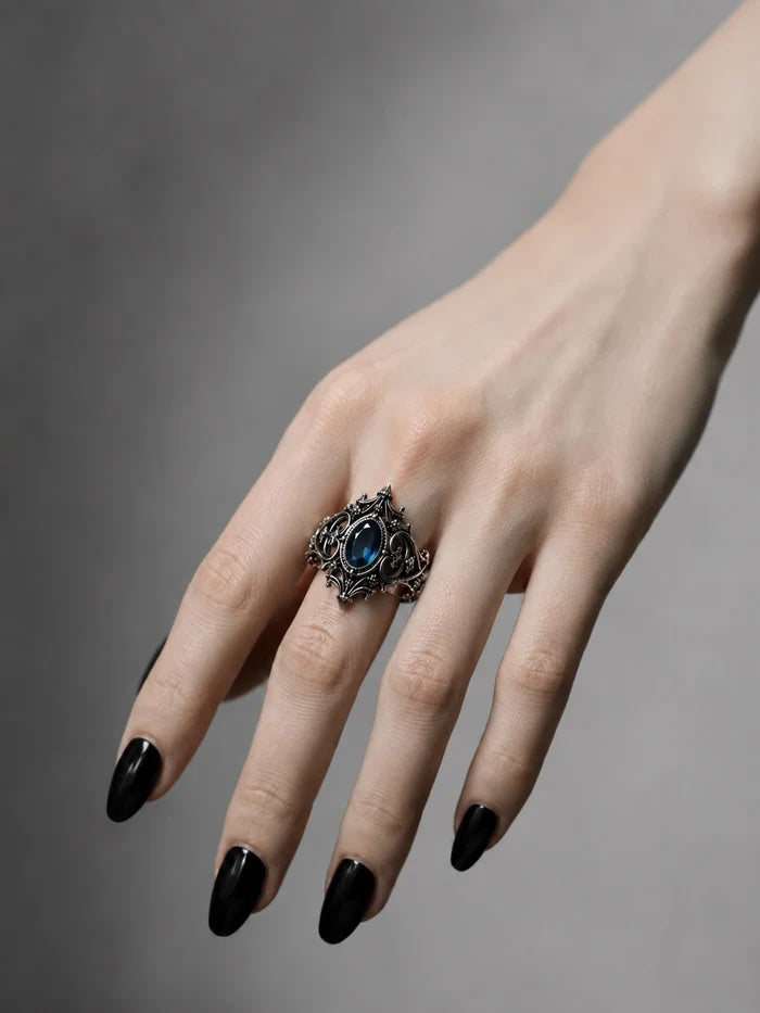 Hand wearing gothic cathedral sanctuary ring with blue topaz — alternative engagement ring in sterling silver