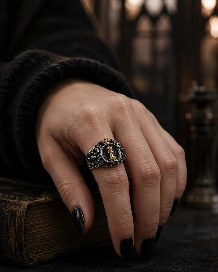 Detail of the gold queen chess piece and crown on the Chess Queen Ring against a blackened ground