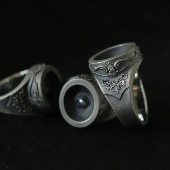 Cyclops rings showing the recessed eye pupil and rococo-baroque relief scrollwork in oxidized silver