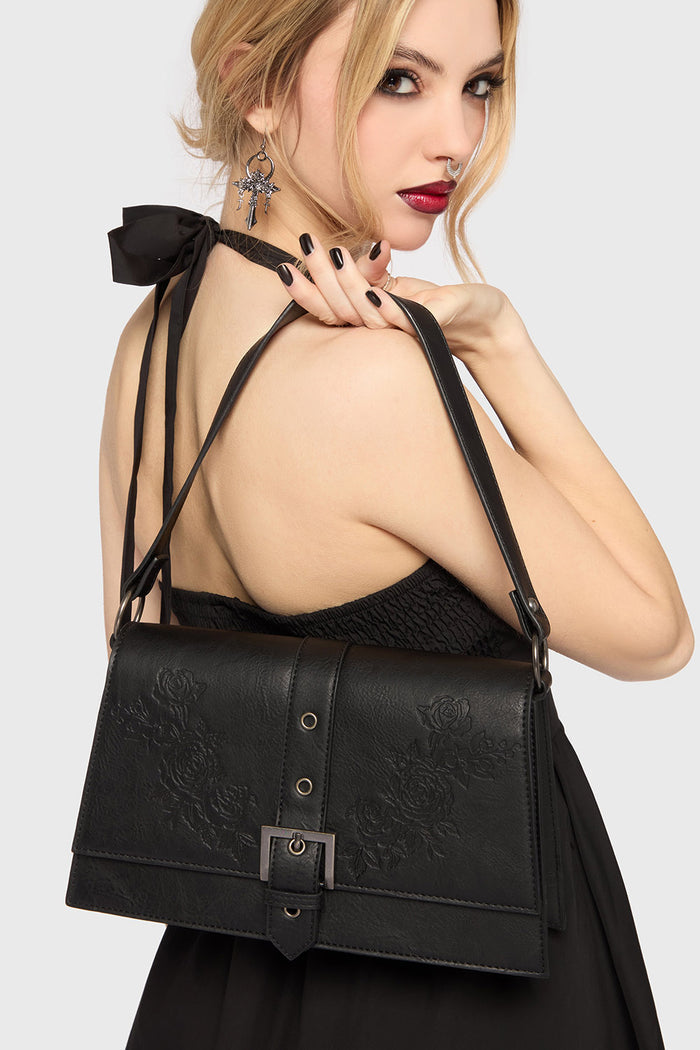 Woman wearing a black lace dress with a matching black gothic handbag on a white background