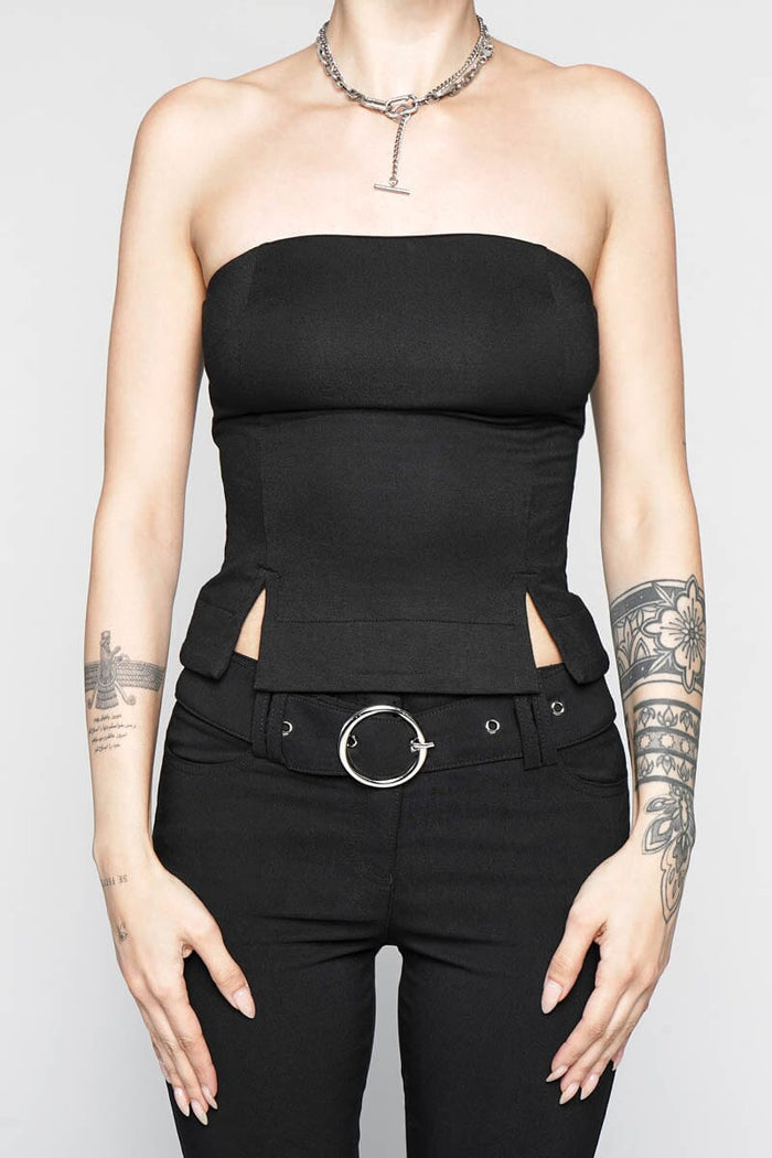 Person wearing a black strapless top and black pants with a belt on a plain background
