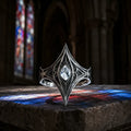 Elven Tear Ring in oxidized sterling silver with marquise moissanite, front view on a stone ledge with cathedral stained glass
