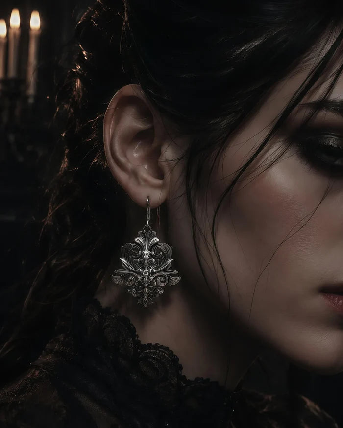 Iris motif gothic dangle earring worn in ear, close-up with candlelight background