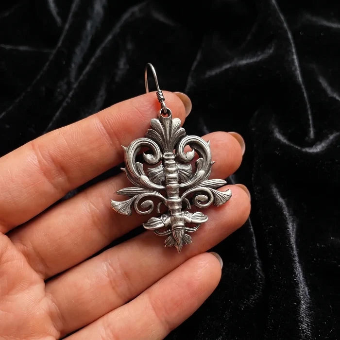 Spine motif earring held in hand showing oxidized silver detail and scale