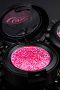Compact makeup case with pink glittery eyeshadow and visible curst brand logo on a dark background