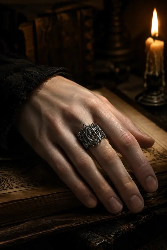 Rampart Crown Ring worn on hand beside a candle, Gothic pierced statement ring
