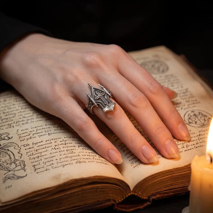 Spire Cross Ring worn on hand resting on an open antique book beside a candle